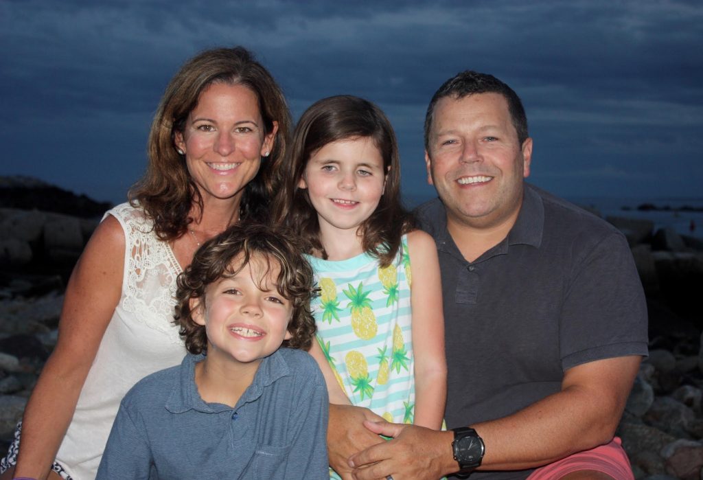 Image description: Jenny and Kevin Cohane pose on the beach with their children Annie and Petey. Annie was diagnosed with Leber congenital amaurosis (LCA) at 3 months of age. Genetic testing later showed a mutation in her CEP290 gene.