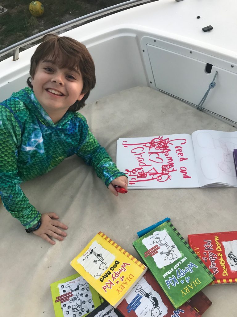 Creed reading and drawing after easily climbing onto a trailered powerboat. 