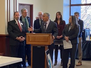 Men and women gathered at a lecturn to speak about rare disease.